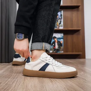 Detail view of white leather German Army Trainer sneakers with blue stripes and gum soles.