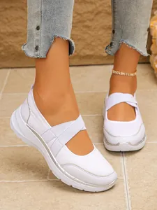 Détail de chaussures de sport blanches pour femmes avec brides croisées et argenté