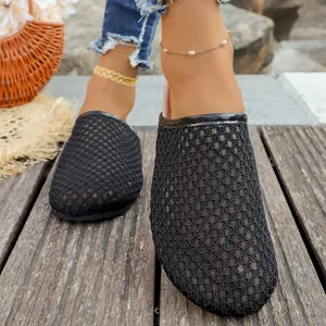 Detailed view of breathable black woven mesh mule slippers worn on feet outdoors