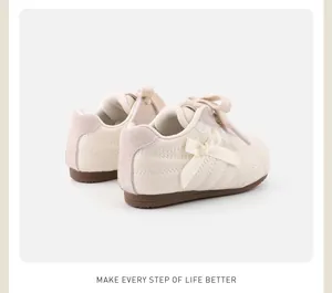 Detailansicht cremefarbener Kinderschuhe mit eleganter Schleife und weicher Sohle.