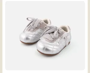 Detail von silbernen Metallic-Kinderschuhen für Mädchen mit Schleife und Steppung.