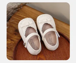 Detailed view of cream white girls' Mary Jane shoes with bow and scalloped trim