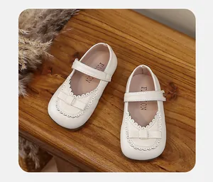 Close-up detail of cream white girl's Mary Jane princess shoes with elegant bow accent