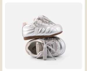 Detaillierte Makroansicht von silbernen Metallic Baby Sneakern mit Schleifen Akzenten