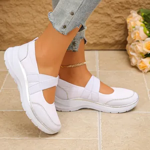 Gros plan de baskets blanches respirantes avec brides croisées et détails argentés.