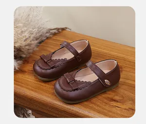 Close-up of brown girl's Mary Jane leather shoes with bow and lace trim details