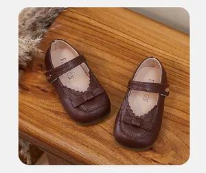 Detailed view of brown girls' Mary Jane shoes with bow and scalloped trim