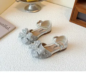 Close-up of girl's silver glitter sandals with rhinestone bow and pearl straps