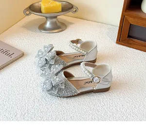 Close-up of silver rhinestone girls' sandals with pearl straps and decorative bows.