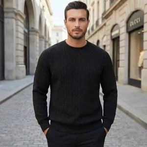 Detail view of a man wearing a black cable knit crew neck sweater in a street setting.