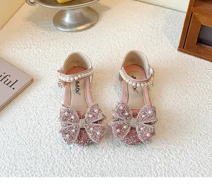 Detailed view of pink princess dress shoes for girls with glitter bows and pearl straps.