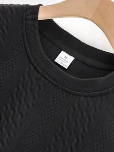 Macro detail of black men's textured jacquard crew neck top focusing on the neck label