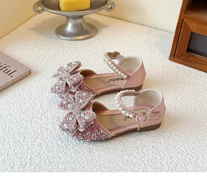 Close-up of pink sparkly girl's princess shoes with rhinestone bow and pearl strap