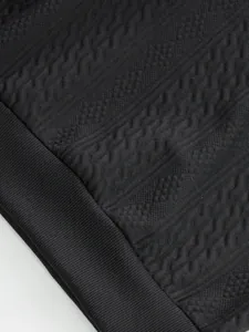 Close-up of black jacquard knit fabric and ribbed hem on men's autumn casual top