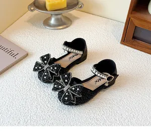 Close-up detail of black girls princess sandals featuring a large rhinestone bow and pearl straps
