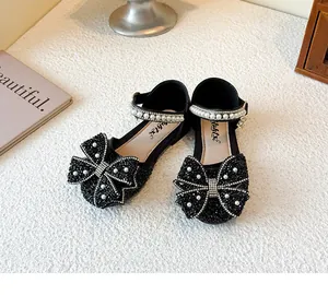 Detail view of black girl's princess shoes with sparkly rhinestone bows and pearls