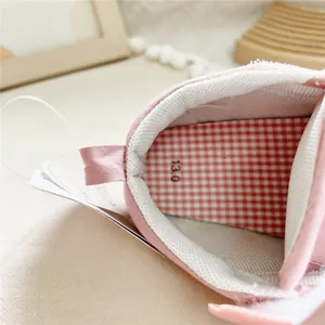 Close-up of pink baby walking shoe interior with checkered lining and tag