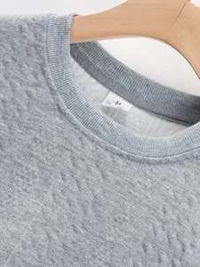 Detailed macro view of gray men's crew neck sweater showing premium diamond jacquard fabric