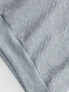 Close-up of grey jacquard fabric texture and ribbed hem on men's sweatshirt