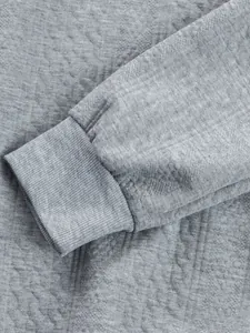 Detail of grey jacquard men's sweatshirt showing ribbed cuff and fabric texture.