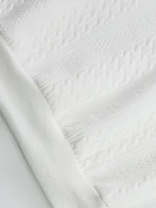 Close-up detail of white jacquard knit fabric and ribbed hem on casual men's top