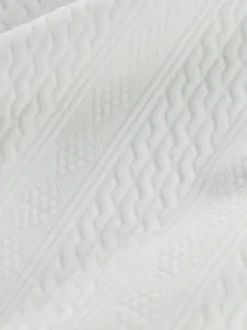 Macro view of intricate white jacquard fabric texture on a casual autumn crew neck men's top.