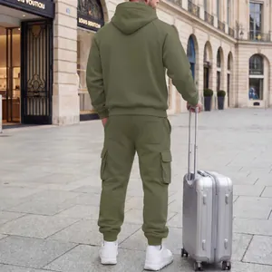 Rear view of man in olive green hooded tracksuit and cargo pants with silver suitcase
