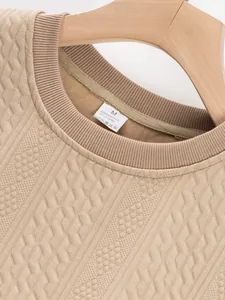 Close-up detail of khaki men's crewneck jacquard sweater with size M label tag.