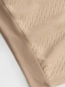 Macro view of the intricate jacquard knit texture on a beige men's knit sweater