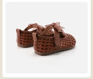 Detail of brown woven children's Mary Janes with chiffon bow on white background.