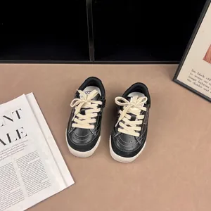 Retro black children's sneakers featuring chunky white laces and hook-and-loop straps