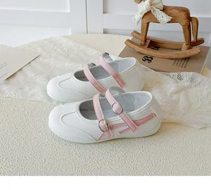 Gros plan de chaussures Mary Jane pour enfants blanches et roses avec doubles brides à boucle.