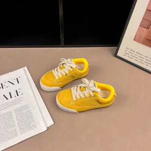 Close-up detail of yellow retro kids sneakers with cream laces and soft sole