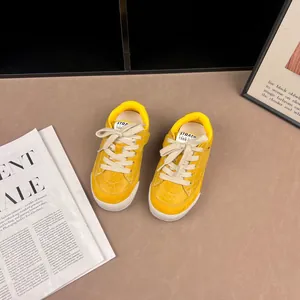 Close-up of yellow retro kids sneakers with soft soles and 'STRAEP 1988' label