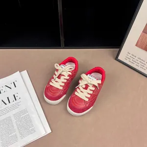 Detailed view of red retro children's sneakers with cream laces and soft soles.
