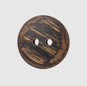 Macro view of a high-end circular ebony wood button with two vintage brass grommets.