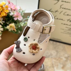 Close-up of girl's cream leather t-strap shoe with knit flower and plaid bow accents