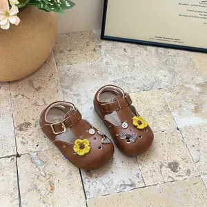 Detailed close-up of brown toddler girl's leather T-strap shoes with cute crochet flowers