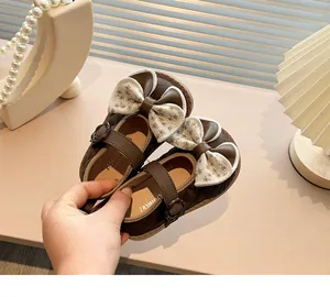 A detailed view of brown girl's princess shoes featuring a floral bow and quilted leather