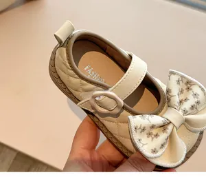 Close-up of girl's Mary Jane shoe with quilted pattern and large floral bow detail.