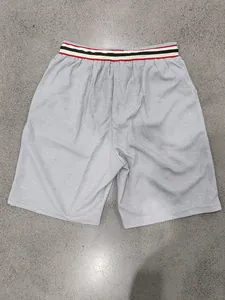 Detail of breathable gray mesh athletic shorts with a stylish striped elastic waistband.