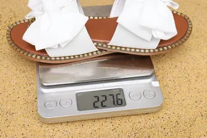 Sandalias planas con lazo blanco para mujer que pesan 227,6 gramos en una báscula