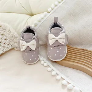 Detailed shot of grey toddler walking shoes with soft soles and white bow accents