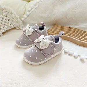 Close-up of purple toddler girls' walking shoes featuring white bows and heart patterns