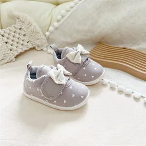 Detailed close-up view of purple baby girls' canvas shoes with white bows and heart patterns