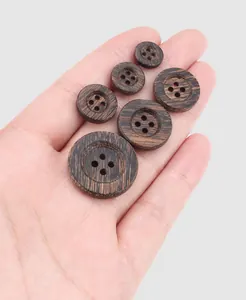 Premium dark natural ebony wood buttons in various sizes displayed on palm for scale