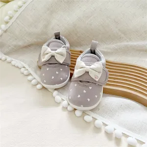 Detailed view of grey baby girl walking shoes with cream bows and heart patterns