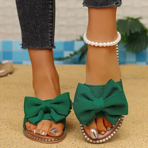 Primer plano del elegante detalle de lazo de tela verde en estas sandalias de moda