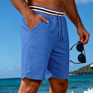 Detailed close-up of blue quick-dry athletic shorts featuring a striped waistband at beach.