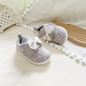Close-up of grey canvas baby girl shoes with heart patterns and soft soles.